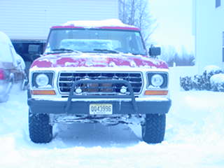 1979 Ford Bronco - A red 1979 Ford Bronco sits in the snow, facing the camera directly.