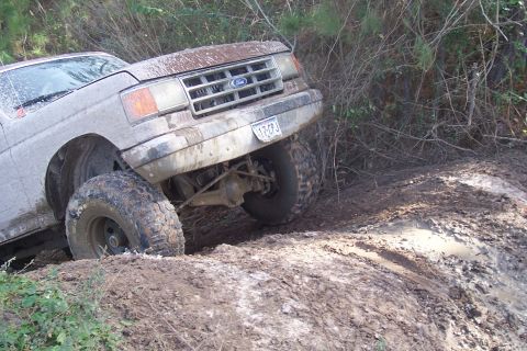1987 Ford Bronco - Muddy 1987 Ford Bronco struggling off-road with front wheel deep in dirt.