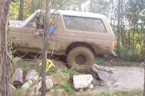 1987 Ford Bronco - This SUV is covered in mud as it navigates a challenging off-road course.