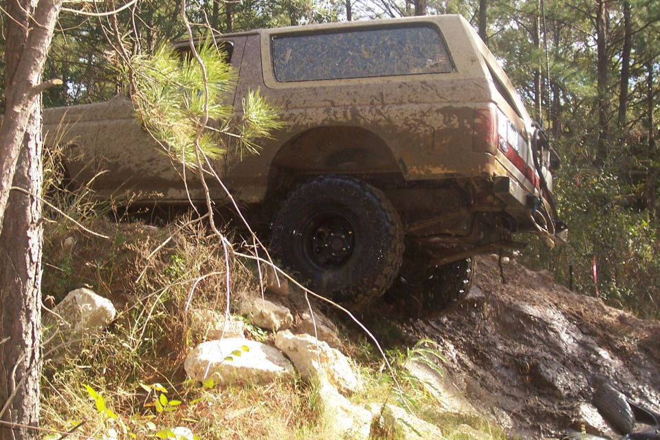 1987 Ford Bronco climbing a muddy hill, side view