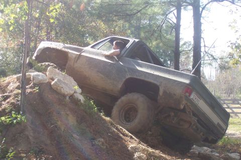 1987 Ford Bronco - This Chevrolet K5 Blazer is navigating a steep, muddy incline on a wooded trail.