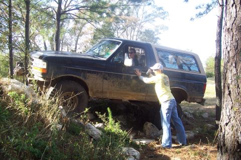 1987 Ford Bronco - A person helps push a Ford Bronco as it navigates a challenging off-road course.