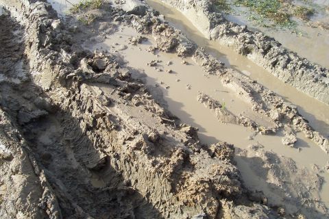 1987 Ford Bronco - Deep tire ruts and muddy water indicate difficult terrain.