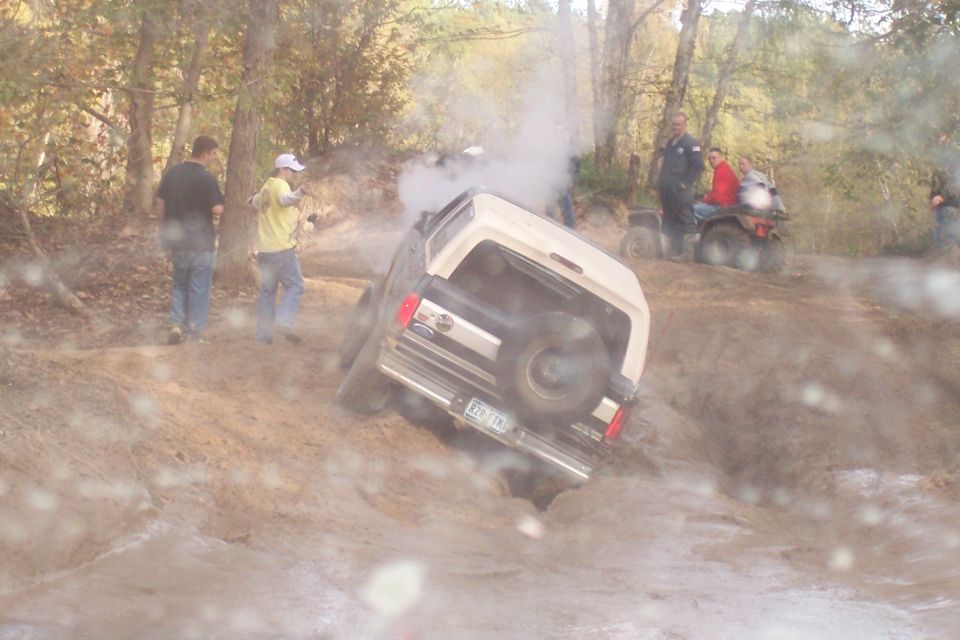 1987 Ford Bronco tilted in mud with spare tire on rear