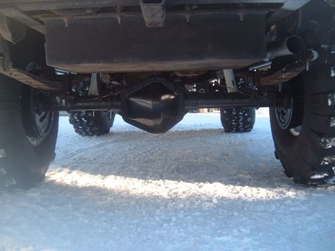1989 Ford Bronco - Undercarriage view of a vehicle's rear axle and suspension components, with large tires visible.