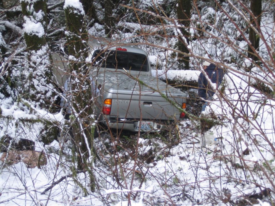 Silver Toyota pickup truck stuck in snow-covered woods