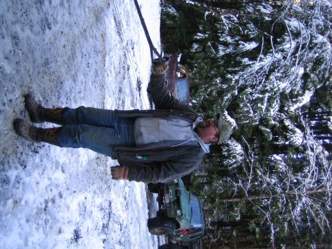 1990 Ford Bronco - A man is winching a green off-road vehicle out of the snow in a wooded area.