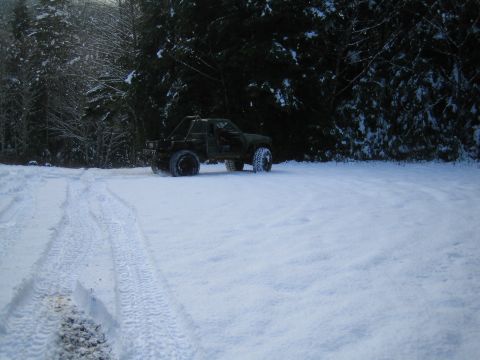 1990 Ford Bronco - An off-road vehicle sits in the snow near a wooded area.