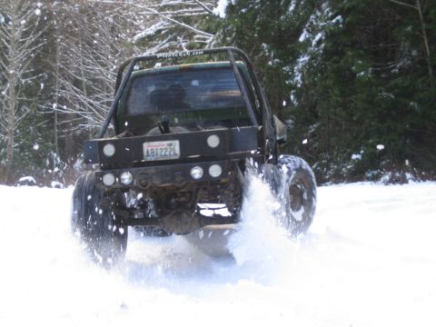 1990 Ford Bronco - A modified truck navigates a snowy forest road, its tires churning through the snow.