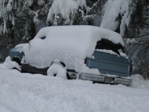 1990 Ford Bronco - A vehicle is almost completely submerged in a heavy snowfall, with only parts of its rear visible.