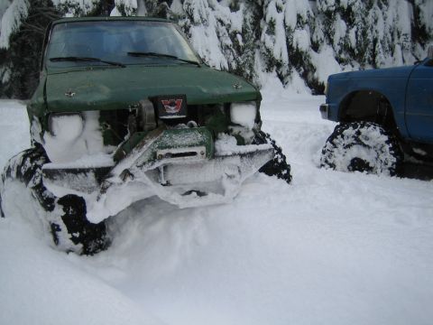1990 Ford Bronco - Off-road trucks buried in snow, showing their modified tires and suspension.