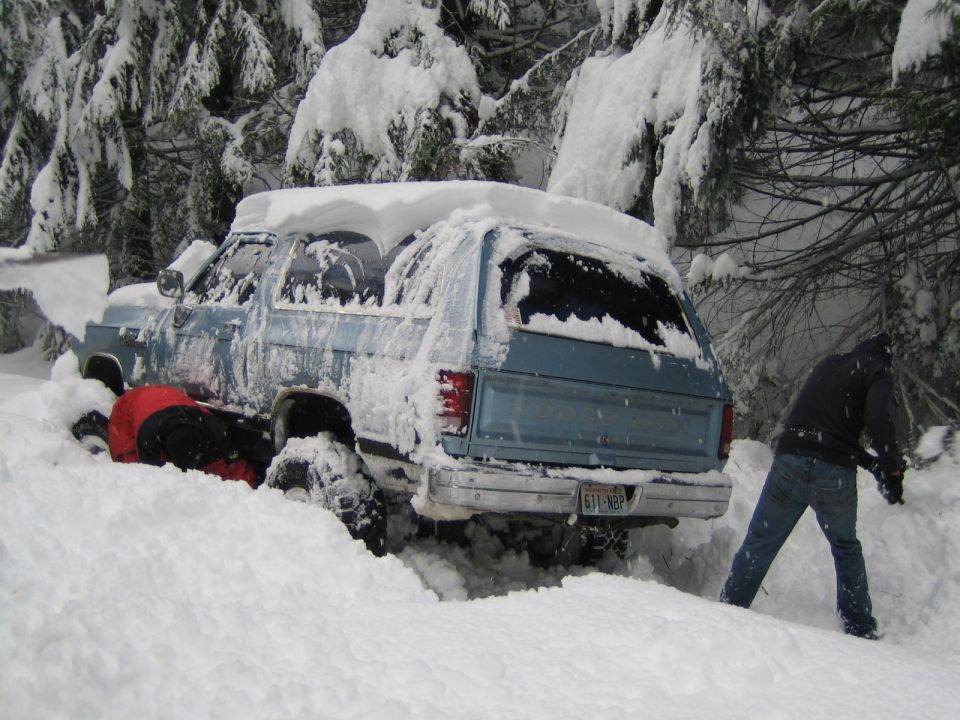 Blue SUV buried in snow, someone digging it out