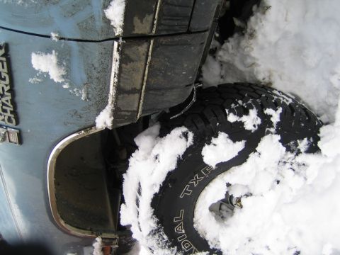 1990 Ford Bronco - Light blue vehicle with 'CHARGER' badging stuck in deep snow.