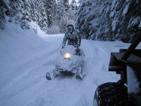 1990 Ford Bronco - Riding a snowmobile through a snow-covered forest trail.