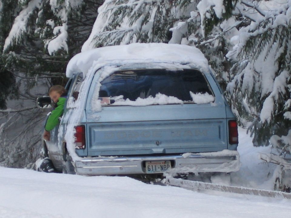 Light blue SUV stuck in snow, kid looking out window. License plate 611-NBP