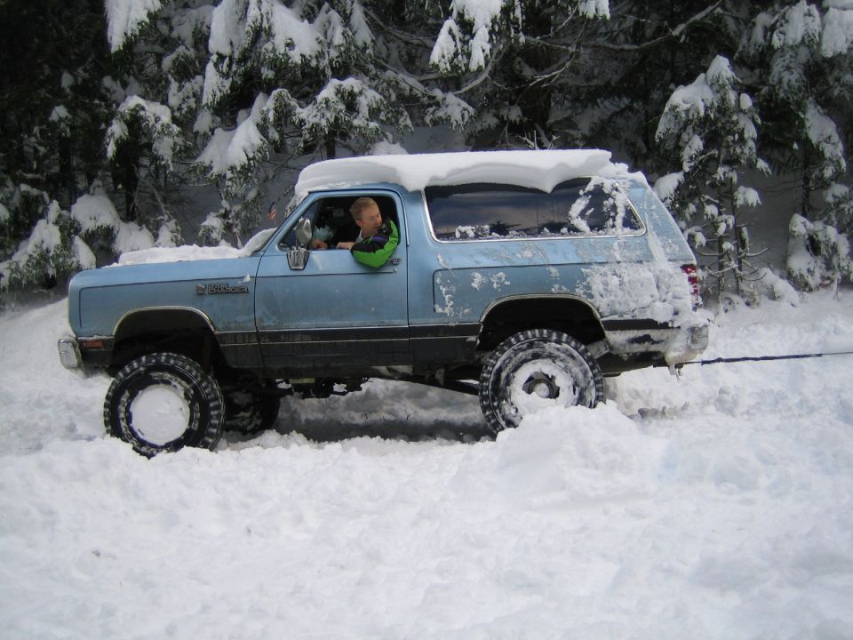 Light blue Dodge Ramcharger stuck in deep snow, driver visible