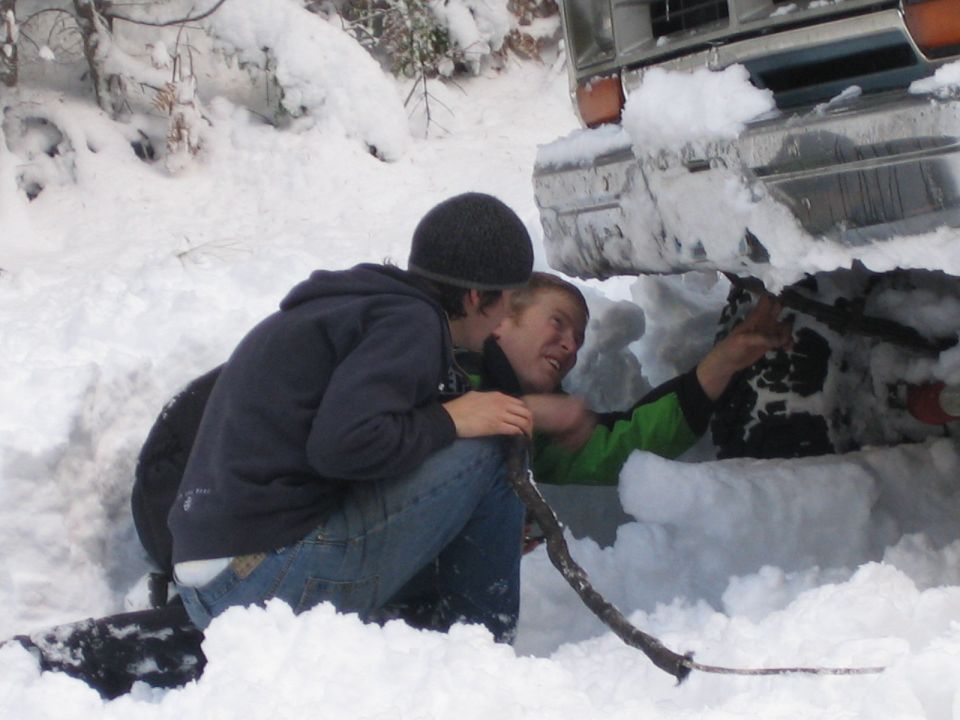 1990 Ford Bronco front end buried in snow with two men working on it