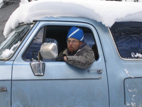 1990 Ford Bronco - A man in a blue hat drives a light blue SUV covered in snow.
