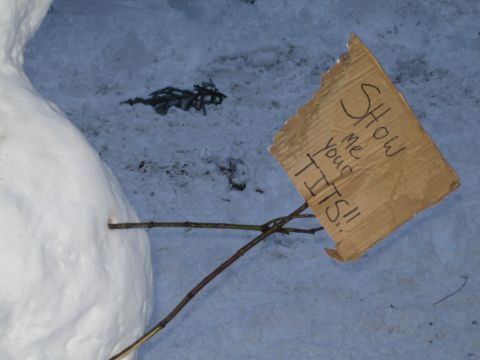1990 Ford Bronco - A snowman in the snow has a cardboard sign attached with sticks, displaying a provocative message.