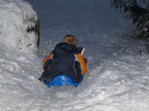 1990 Ford Bronco - A child sits on a blue sled, engrossed in a book while in a snowy environment.
