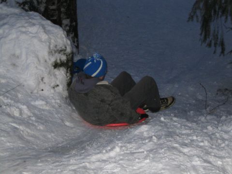 1990 Ford Bronco - A person is sledding down a snow-covered slope on a red sled.