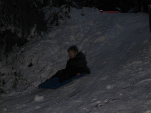 1990 Ford Bronco - Child sledding down a snowy hill at night.