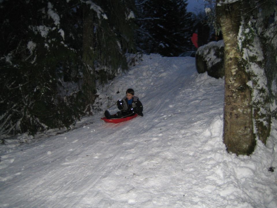 Child sledding down a snowy hill in winter