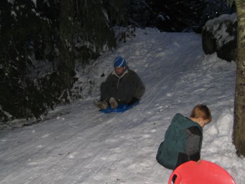 1990 Ford Bronco - Two people enjoy a nighttime sledding adventure down a snowy hill surrounded by trees.