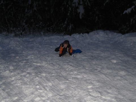 1990 Ford Bronco - A child is about to go sledding down a snowy hill at night.