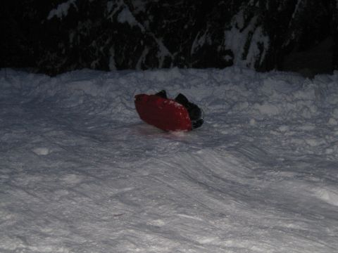 1990 Ford Bronco - A red sled rests on a snow-covered slope at night, with dark trees in the background.