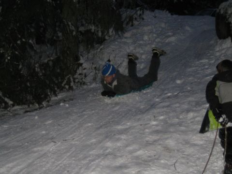 1990 Ford Bronco - People enjoy sledding down a snow-covered hill in the dark.
