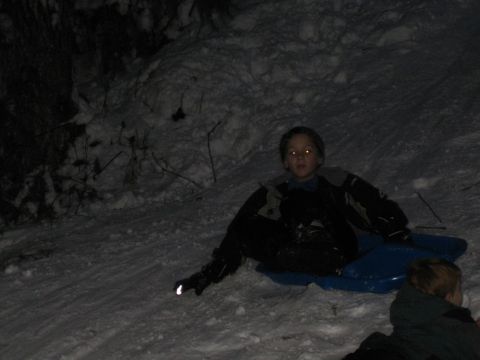 1990 Ford Bronco - Children enjoy a snowy night on sleds, with one child's eyes reflecting light.