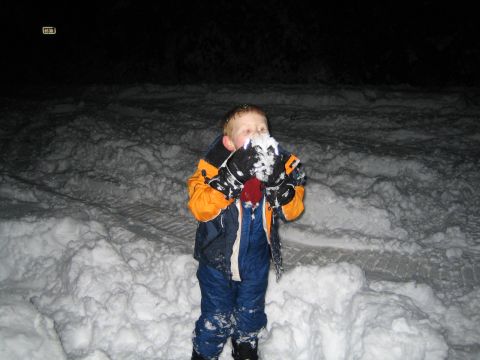1990 Ford Bronco - A child stands in the snow, holding a clump of snow in their hands.