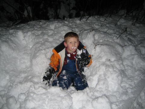 1990 Ford Bronco - A young child is buried in snow, with snow on their face and jacket.