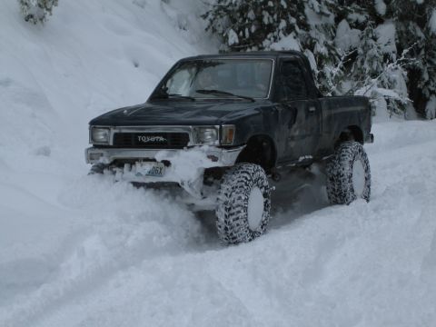 1990 Ford Bronco - Toyota pickup truck navigating a snowy terrain with its large off-road tires.
