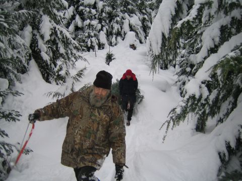 1990 Ford Bronco - Two individuals trek through a snow-laden forest, carrying freshly cut Christmas trees.