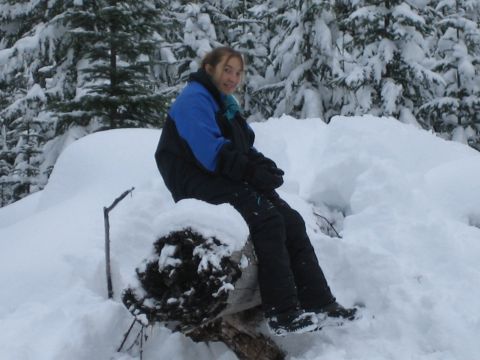 1990 Ford Bronco - A person sits on a log in a snowy forest environment.