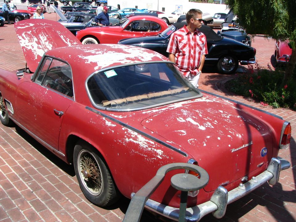 Red coupe with peeling paint, rear quarter view. Wire wheels