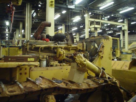 1966 International School Bus - A yellow engine assembly for heavy machinery is visible in a factory setting.
