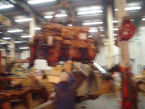 1966 International School Bus - Industrial engine being lifted by a crane in a workshop setting.