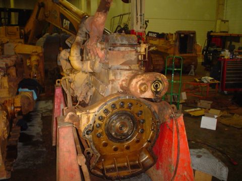 1966 International School Bus - A disassembled engine is on display in a workshop, with heavy machinery visible behind it.