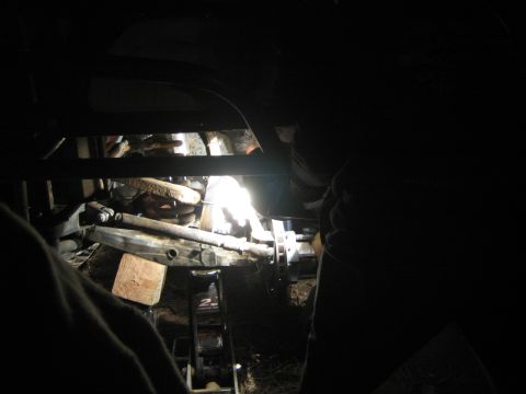 1990 Ford Bronco - bright welding arc lights up someone making repairs underneath a race vehicle's tube chassis at night.