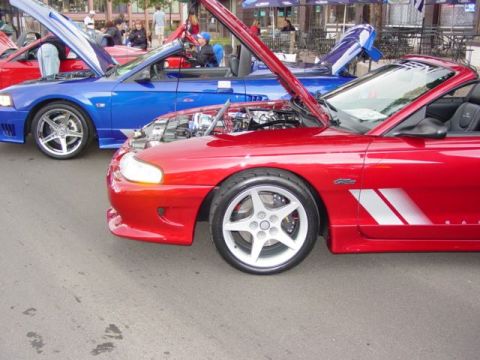 1996 Ford Probe - Two convertible sports cars, one red and one blue, are parked with their hoods open.