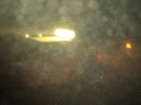 1990 Ford Bronco - glowing roof light and red bodywork of a race vehicle are barely visible through a dusty, smeared lens at night.