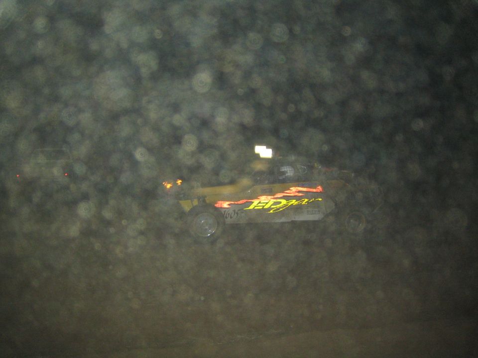 Yellow off-road race buggy with flame graphics, dusty night lens