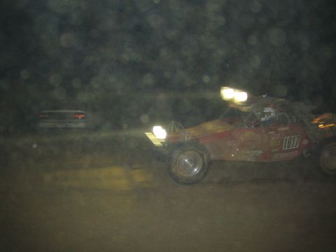 1990 Ford Bronco - red off-road race buggy numbered 1617 races through the dust at night with its lights on.