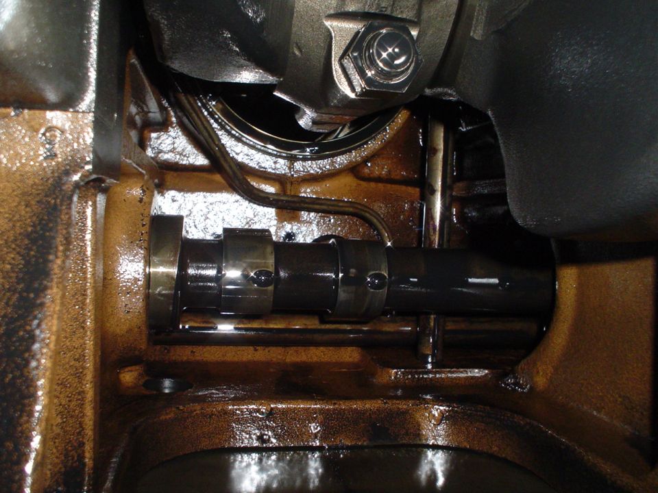 Close-up of an engine's camshaft and crankshaft, covered in oil