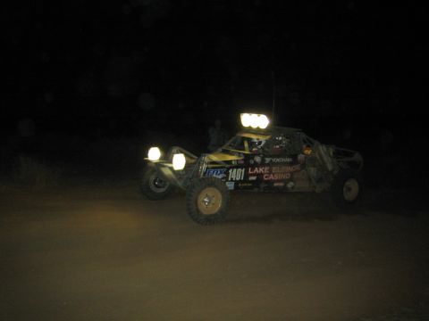 1990 Ford Bronco - black and yellow off-road race buggy numbered 1401 with a Lake Elsinore Casino decal and roof lights runs at night.