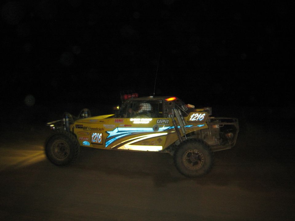 Yellow and blue off-road race buggy number 1216 with roof lights at night
