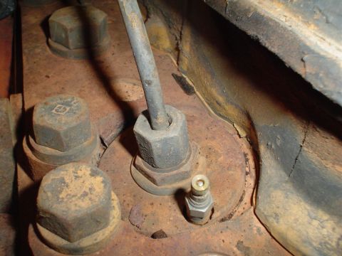 1966 International School Bus - Detail of an engine part, showing bolts and a small fitting, with visible rust and wear.